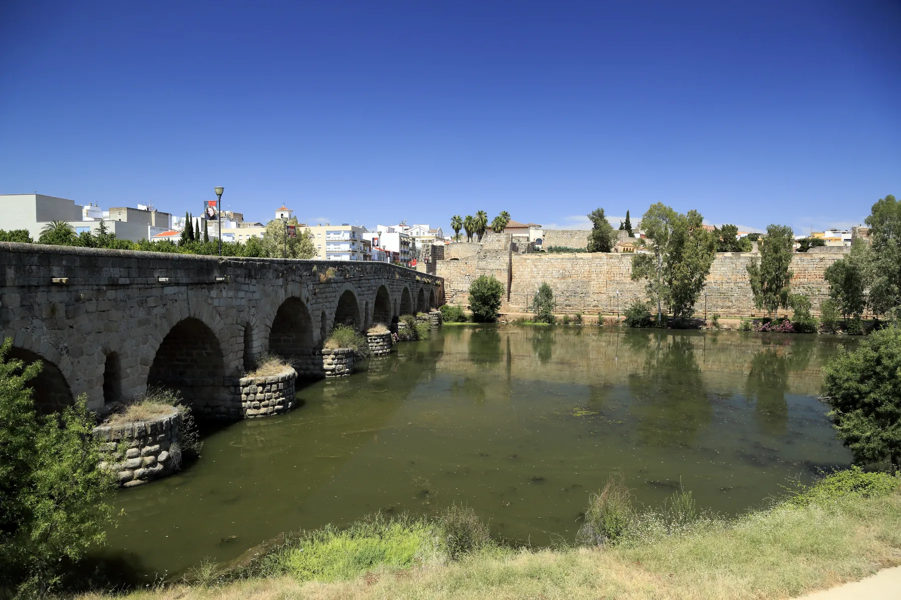 Arcos del puente romano de Mérida sobre el Guadiana, con la alcazaba al fondo.