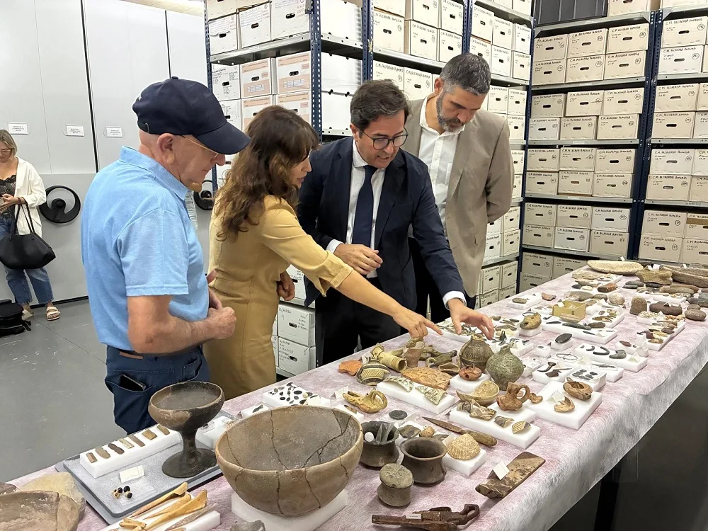 Varias personas observan las piezas arqueológicas dispuestas sobre una mesa en el almacén del Museo de Almería.