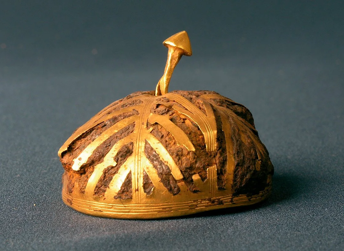 Semiesfera hueca ¿casco? de hierro recubierto de láminas de oro. Se puede observar como la corrosión del hierro ha cubierto y deformado algunas láminas de oro. Fotografía Museo de Villena (Alicante). Sin escala, diámetro máximo 4,5 cm. -