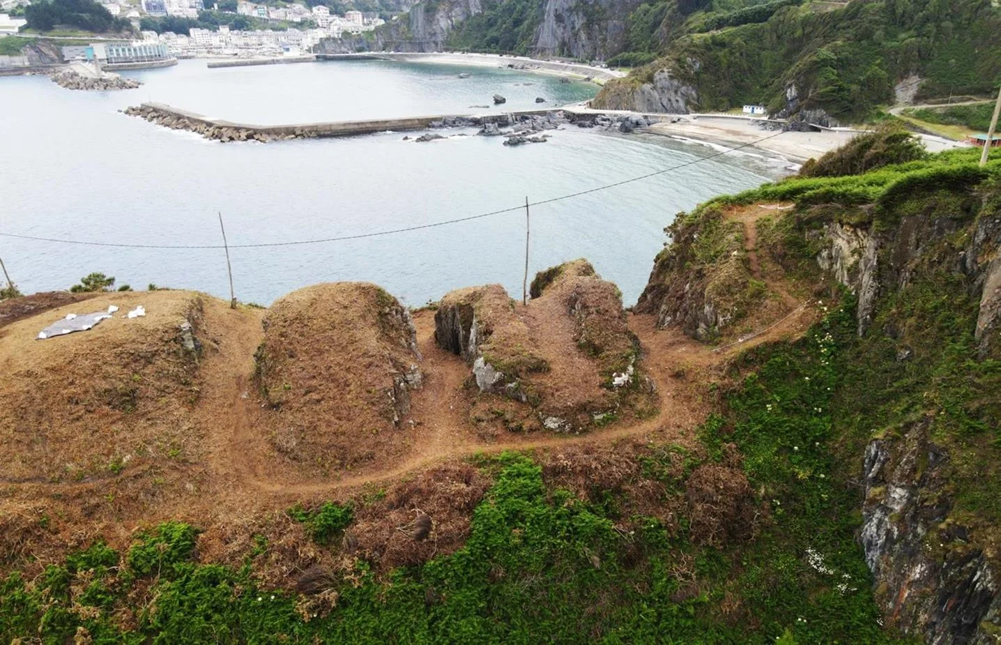 Fosos excavados en la roca del castro costero de Puntamuyeres, con la bahía de Luarca al fondo